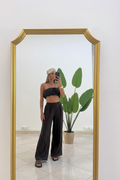 Modella in piedi con pantaloni neri fluidi