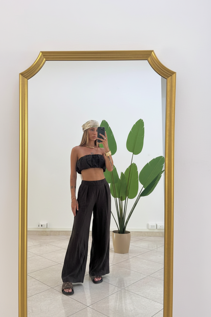 Modella in piedi con pantaloni neri fluidi